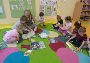 Dzieci wraz z panią dyrektor Magdaleną Siupą oglądają książki, które trzymają w dłoniach.